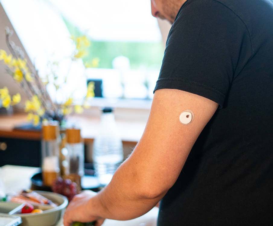 Persoon met glucosesensor op is bezig in de keuken